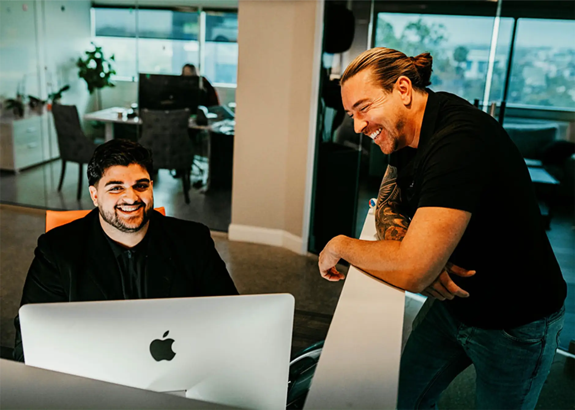 Two Sunshine State Law Firm team members laughing at a desk in the office