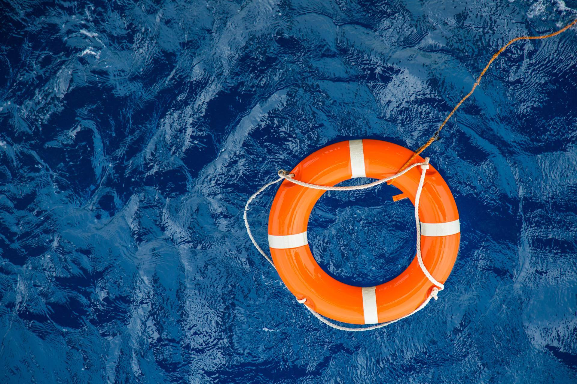 A red and white life ring floating in clear blue pool water