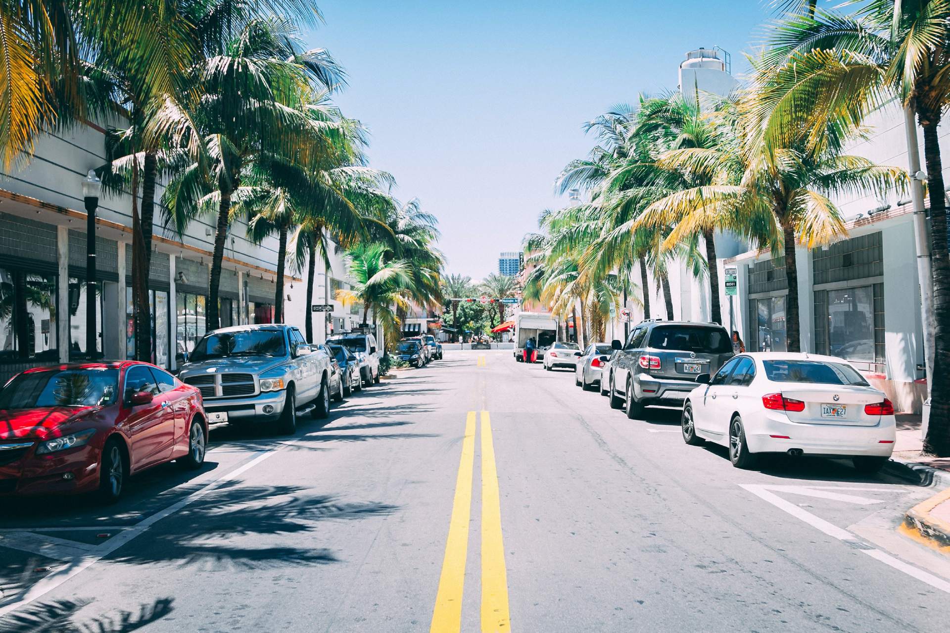 A palm-lined street with sidewalks and a crosswalk on a sunny Florida day