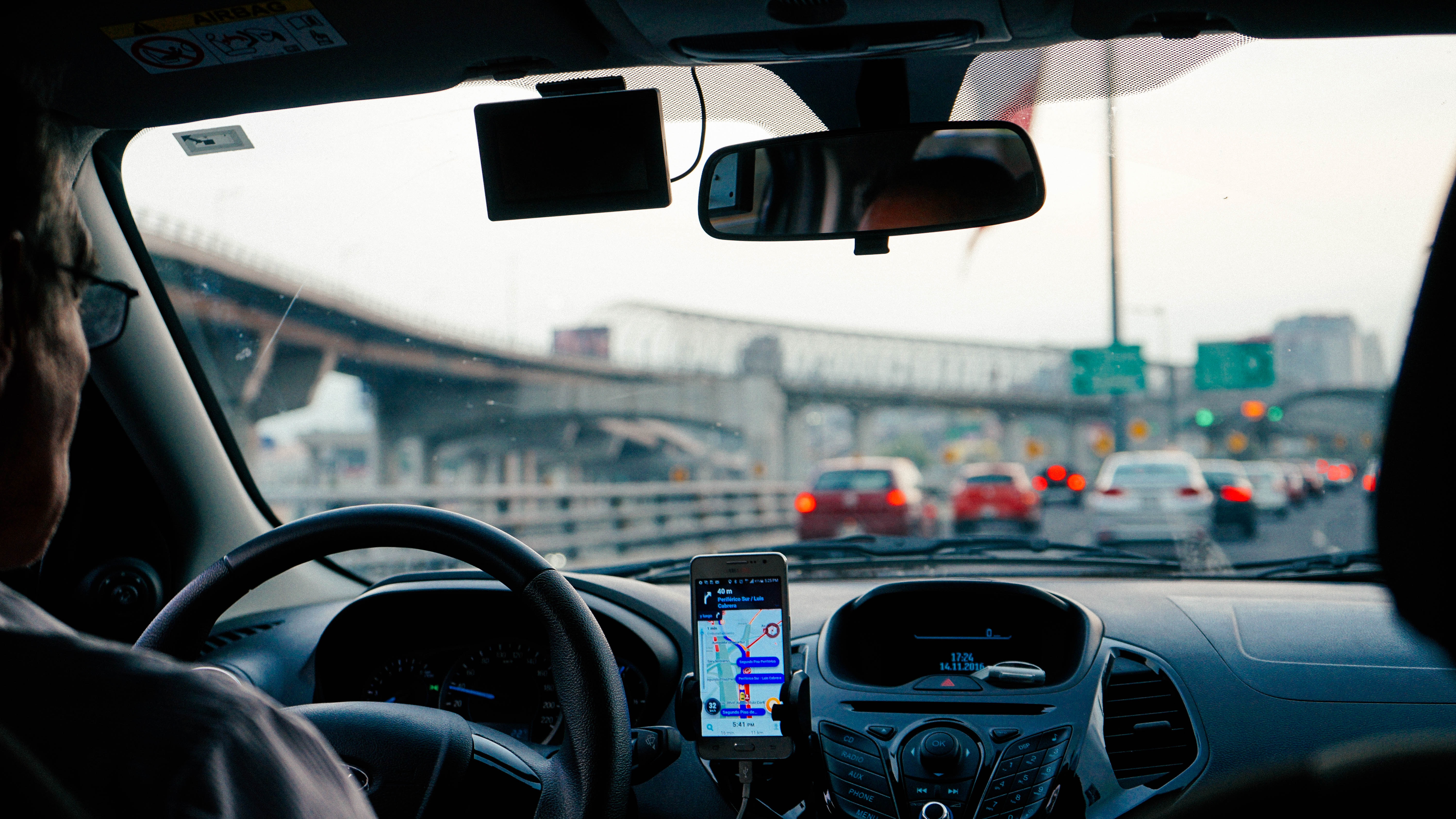 A driver’s view of highway traffic with a navigation app on a phone mounted on the dashboard